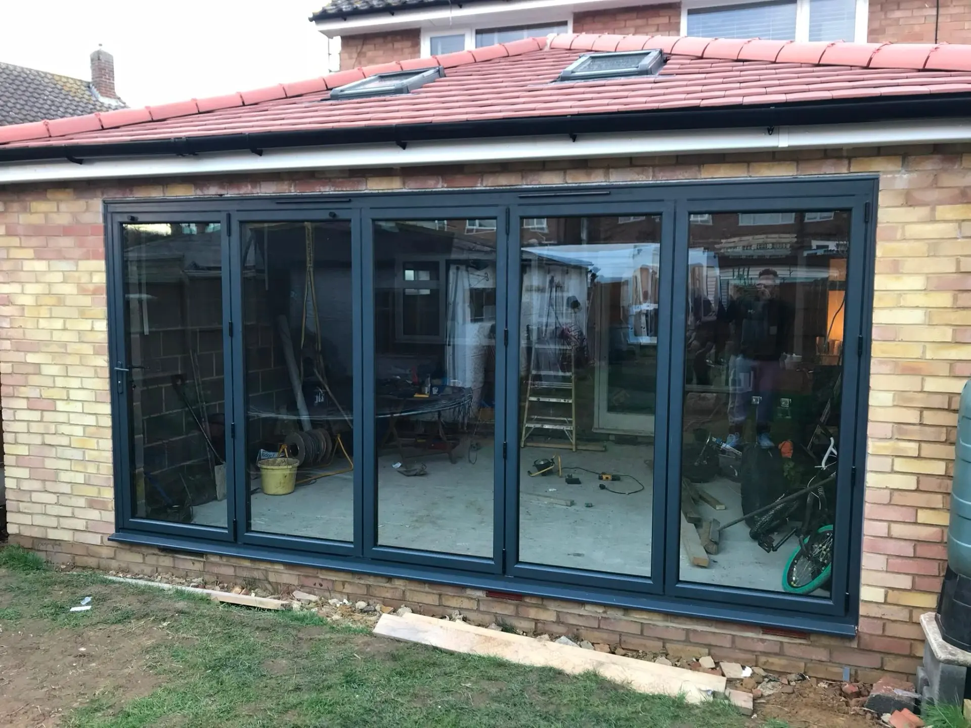 Five-panel anthracite grey aluminium bi-fold doors fitted to a brick garden room extension