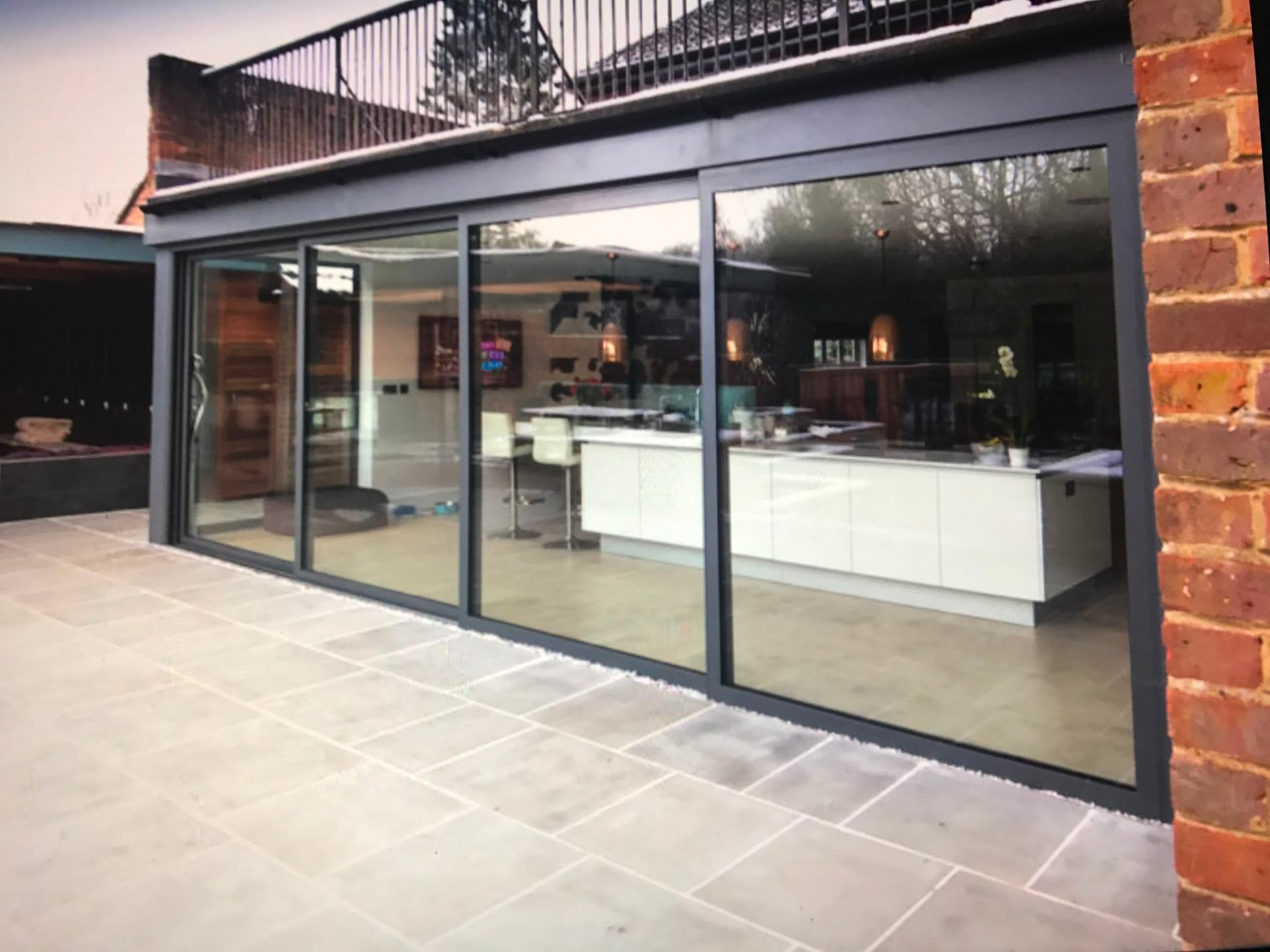 Anthracite grey aluminium sliding patio doors opening onto a paved terrace